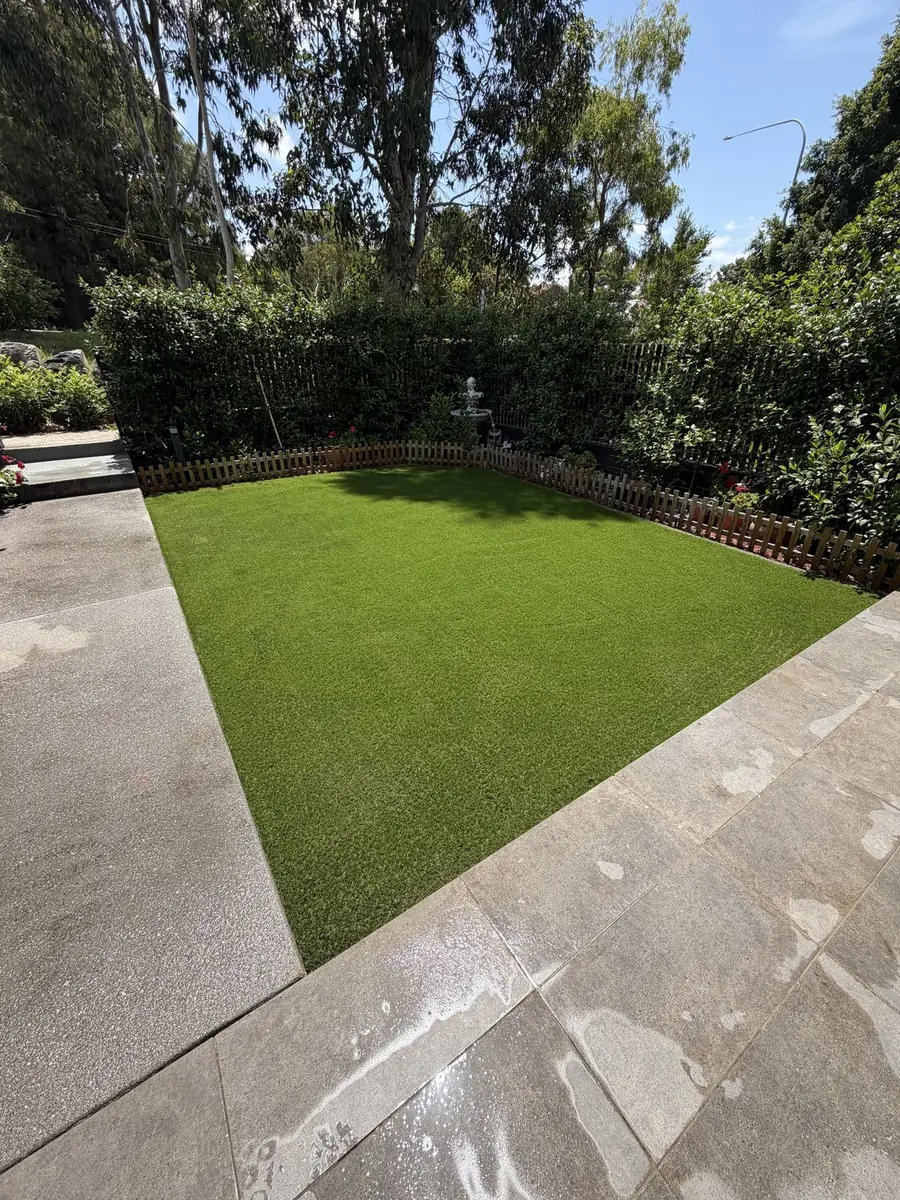 Artificial lawn surrounded by hedges and a sandstone path