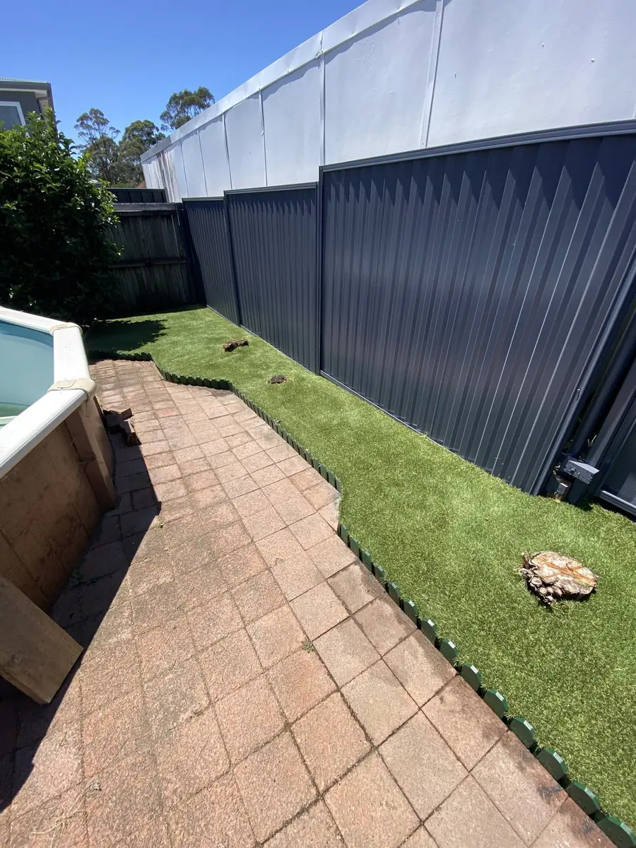 Artificial grass along a side fence beside paving